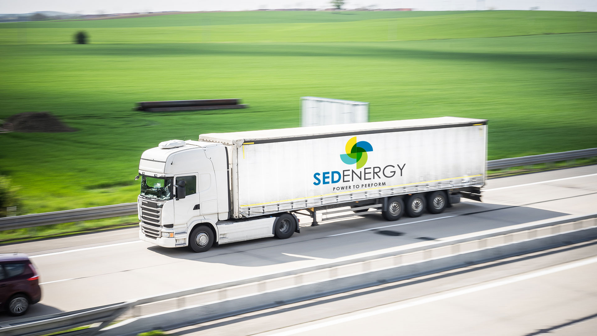 SED-Energy-Truck-Driving-Next-to-Green-Fields-on-Highway SED-Energy-Truck-Driving-Next-to-Green-Fields-on-Highway